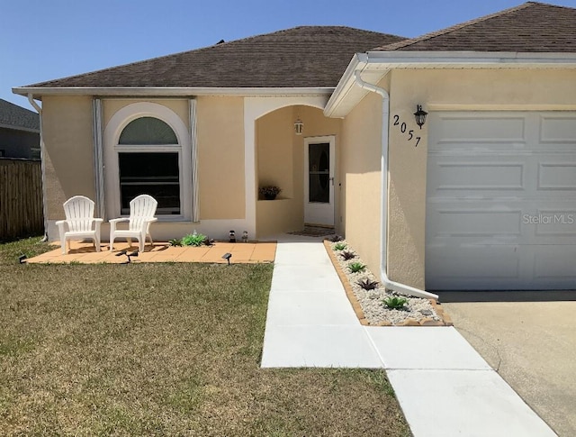 entrance to property with stucco siding, roof with shingles, and an attached garage