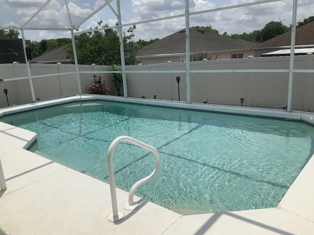 view of swimming pool featuring a fenced backyard and glass enclosure