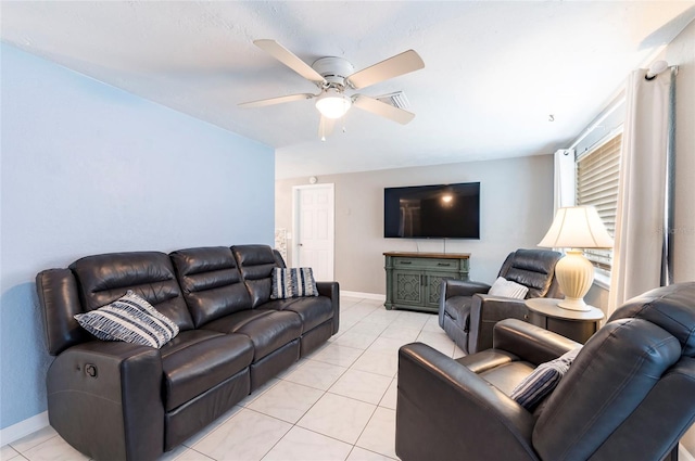 living area featuring a ceiling fan, baseboards, and light tile patterned flooring