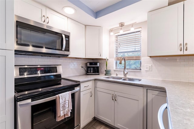 kitchen with appliances with stainless steel finishes, a sink, white cabinets, and decorative backsplash