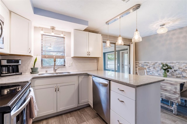 kitchen featuring stainless steel dishwasher, a sink, light wood-type flooring, electric range oven, and a peninsula