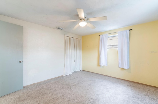 carpeted spare room featuring a ceiling fan and baseboards