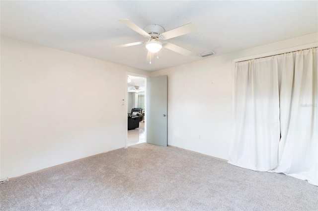 unfurnished room featuring a ceiling fan, light colored carpet, and baseboards