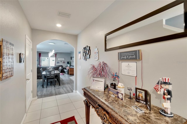 hall featuring arched walkways, light tile patterned floors, baseboards, and recessed lighting