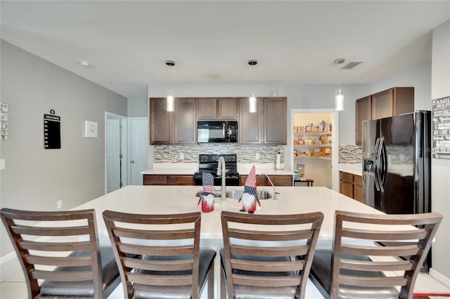 kitchen featuring black appliances, decorative backsplash, light countertops, and hanging light fixtures