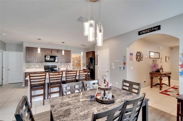 dining space with arched walkways, light tile patterned floors, a chandelier, and baseboards