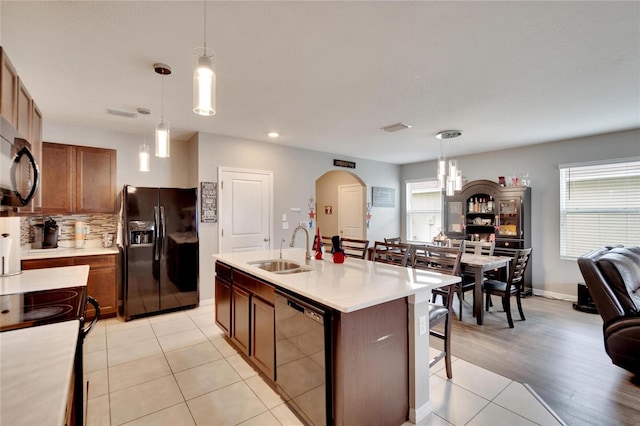 kitchen featuring black appliances, a sink, arched walkways, light countertops, and recessed lighting