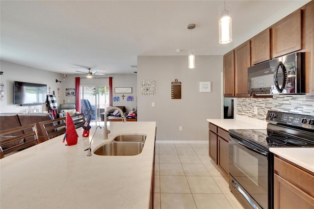kitchen featuring electric range, a sink, tasteful backsplash, light countertops, and decorative light fixtures