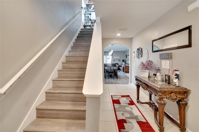 staircase featuring arched walkways, tile patterned flooring, and recessed lighting