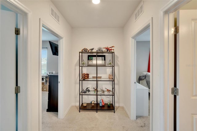 hallway featuring carpet and baseboards