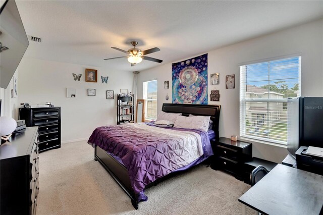 carpeted bedroom with a ceiling fan, baseboards, and a desk