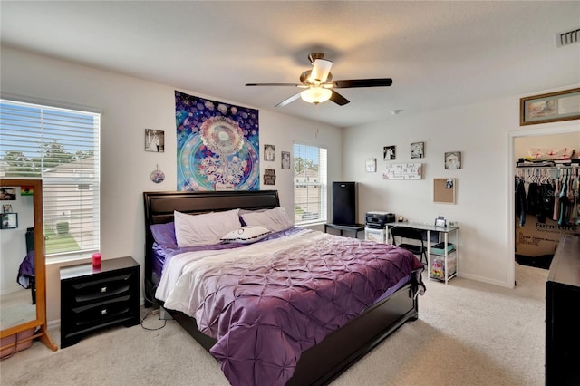 bedroom with carpet, ceiling fan, a walk in closet, and baseboards
