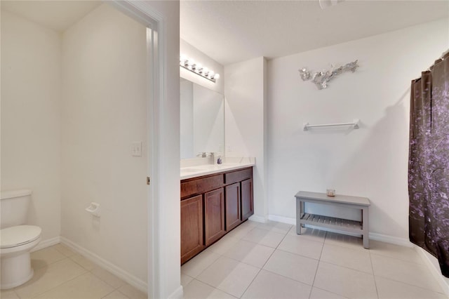 bathroom featuring toilet, tile patterned flooring, vanity, and baseboards