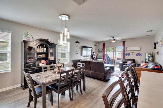 dining room featuring light wood-type flooring, a ceiling fan, and baseboards