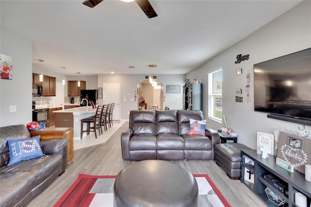 living room featuring light wood-type flooring, ceiling fan, and arched walkways