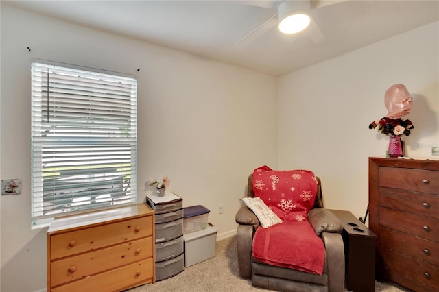 living area with a ceiling fan, light carpet, and baseboards