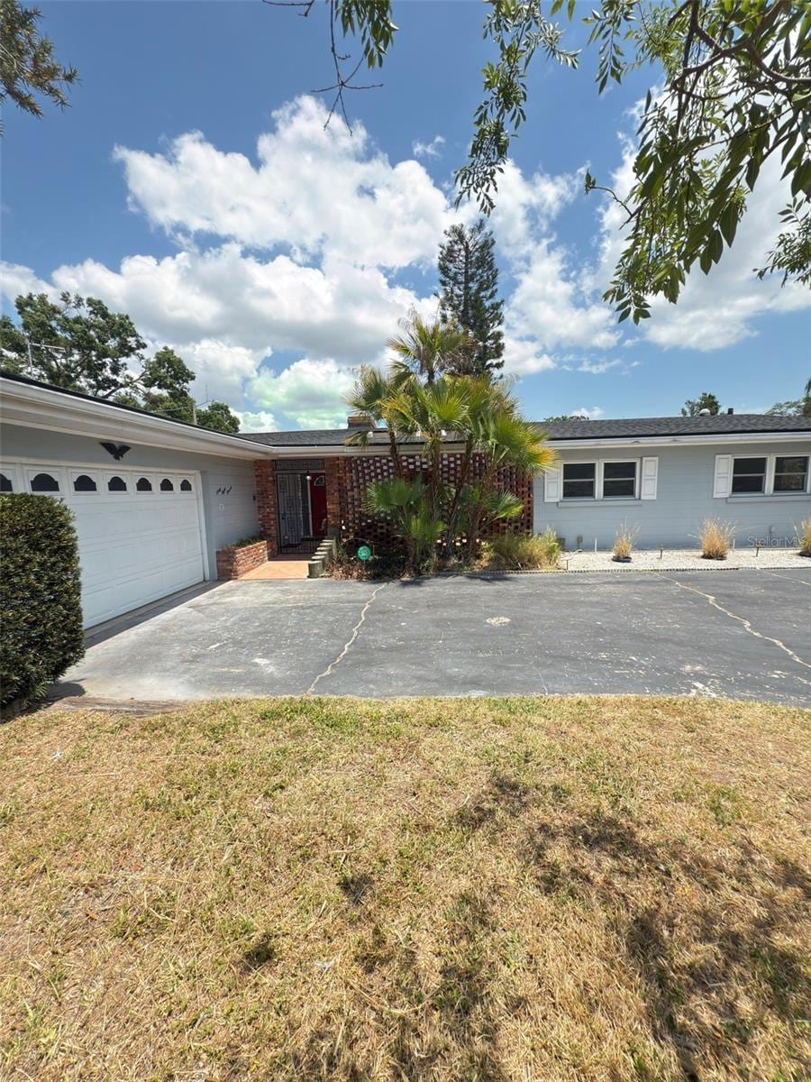 ranch-style house featuring driveway, an attached garage, and a front yard