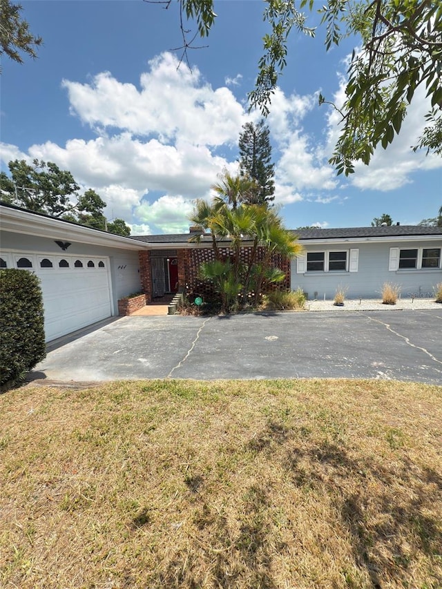 ranch-style house featuring driveway, an attached garage, and a front yard