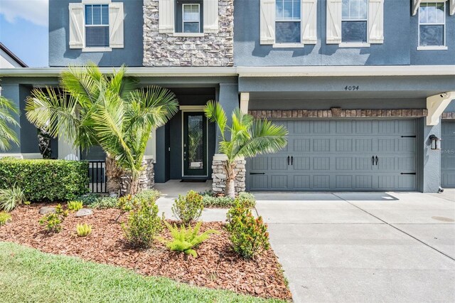 4094 Windcrest Dr, Wesley Chapel, FL 33544 - property entrance with concrete driveway, stone siding, stucco siding, and a garage
