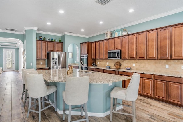 4094 Windcrest Dr, Wesley Chapel, FL 33544 - kitchen with stainless steel appliances, arched walkways, a large island with sink, and visible vents