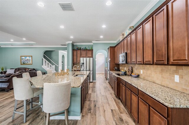 4094 Windcrest Dr, Wesley Chapel, FL 33544 - kitchen with a sink, light wood-type flooring, visible vents, arched walkways, and appliances with stainless steel finishes