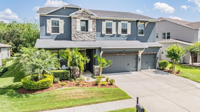 4094 Windcrest Dr, Wesley Chapel, FL 33544 - view of front facade featuring stone siding, a garage, stucco siding, a front lawn, and driveway