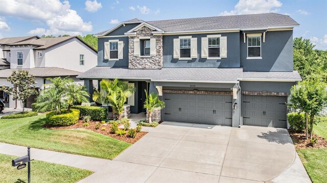 4094 Windcrest Dr, Wesley Chapel, FL 33544 - craftsman-style house featuring stone siding, a shingled roof, stucco siding, and a garage