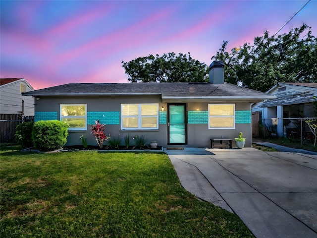ranch-style home with a chimney, a front yard, stucco siding, and fence