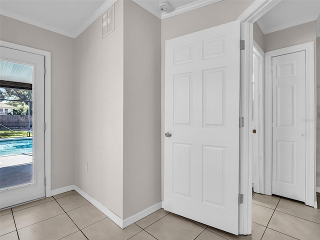 doorway featuring crown molding, baseboards, light tile patterned floors, and visible vents
