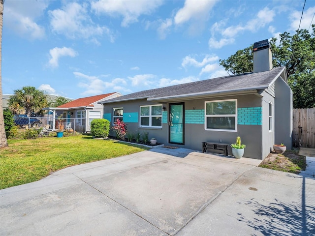 ranch-style house with a chimney, fence, stucco siding, roof with shingles, and a front lawn