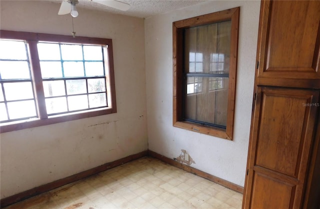 spare room with baseboards, light floors, and a ceiling fan