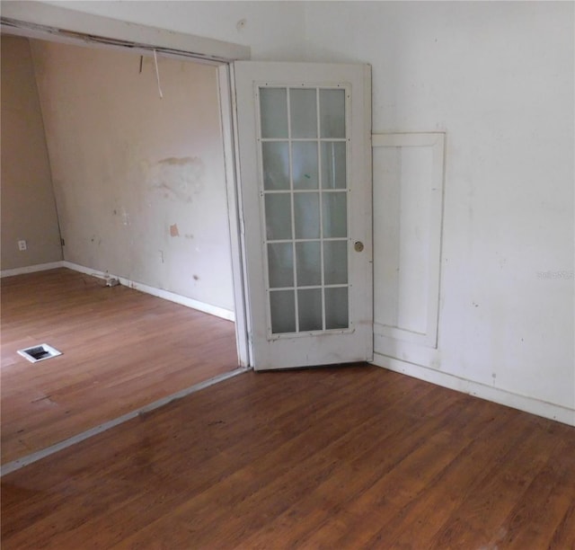 empty room with baseboards, visible vents, and wood finished floors
