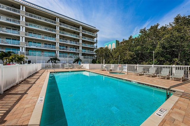 community pool with fence, a community hot tub, and a patio area