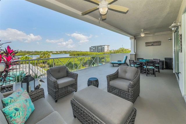 view of patio featuring a ceiling fan, a balcony, outdoor dining space, and a water view
