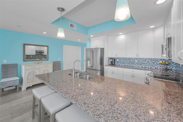 kitchen with light stone counters, tasteful backsplash, appliances with stainless steel finishes, and a sink