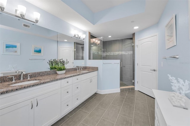 bathroom featuring a stall shower, visible vents, a sink, and double vanity