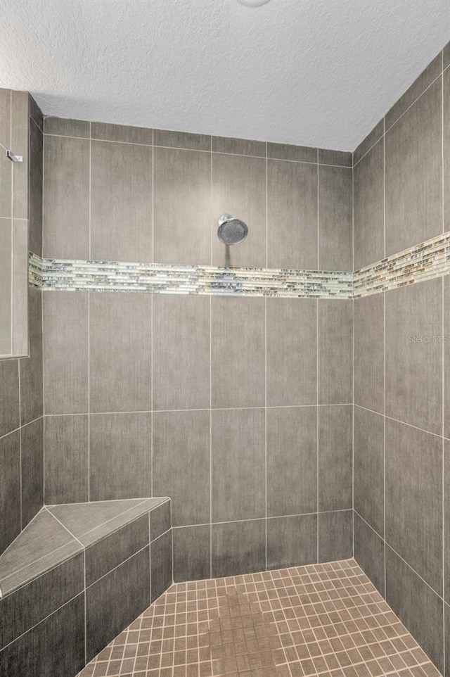 full bath featuring a textured ceiling and a tile shower