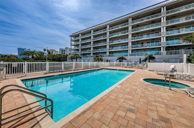 pool with a hot tub, fence, and a patio area