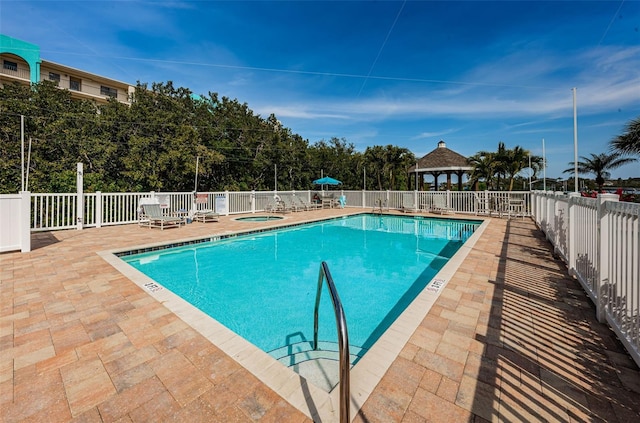 pool featuring a gazebo, a patio area, a community hot tub, and fence