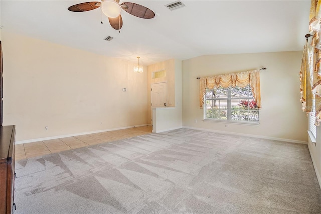 spare room featuring lofted ceiling, light carpet, ceiling fan with notable chandelier, and visible vents