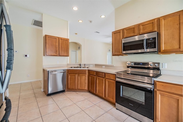 kitchen with a sink, visible vents, arched walkways, light countertops, and appliances with stainless steel finishes