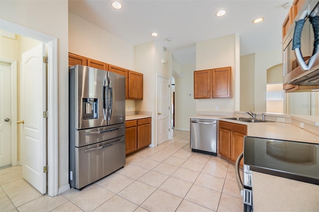 kitchen featuring a sink, brown cabinetry, light tile patterned floors, and appliances with stainless steel finishes
