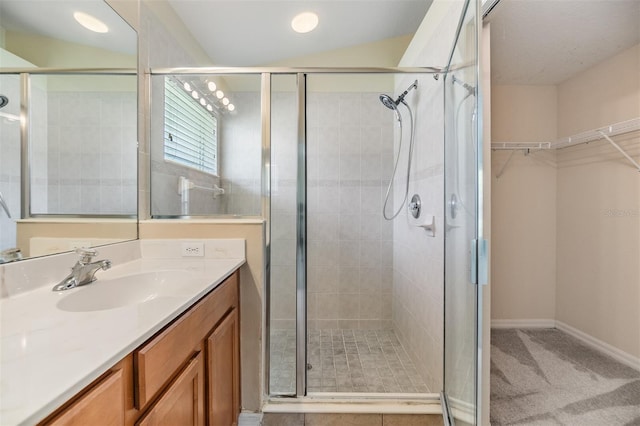 bathroom with a shower stall, baseboards, vanity, and a walk in closet