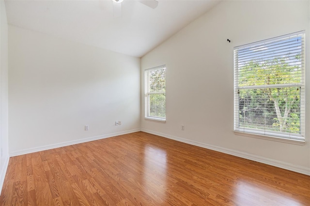 spare room with a ceiling fan, vaulted ceiling, light wood-style flooring, and baseboards