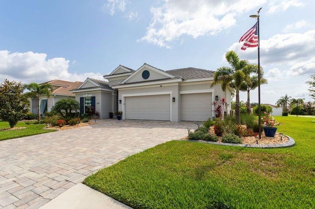 view of front of property with a garage, decorative driveway, a front lawn, and stucco siding