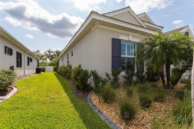 view of home's exterior with stucco siding, a lawn, and central AC unit