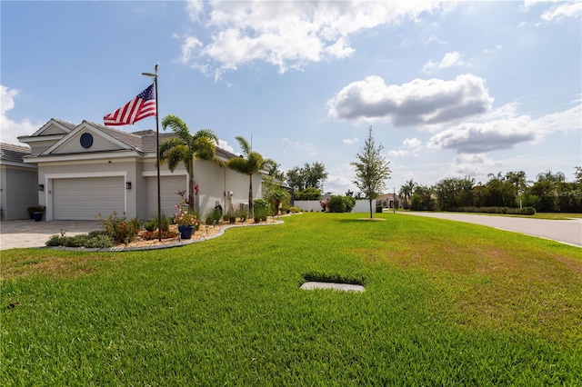 view of green lawn with an attached garage and driveway