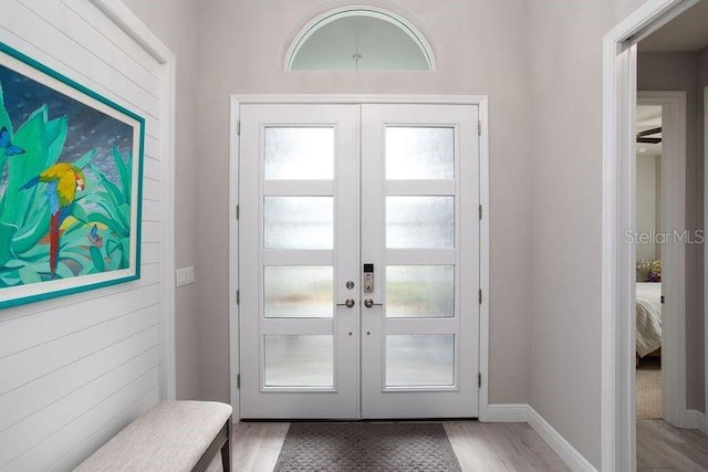 doorway to outside with french doors, light wood-style floors, and baseboards