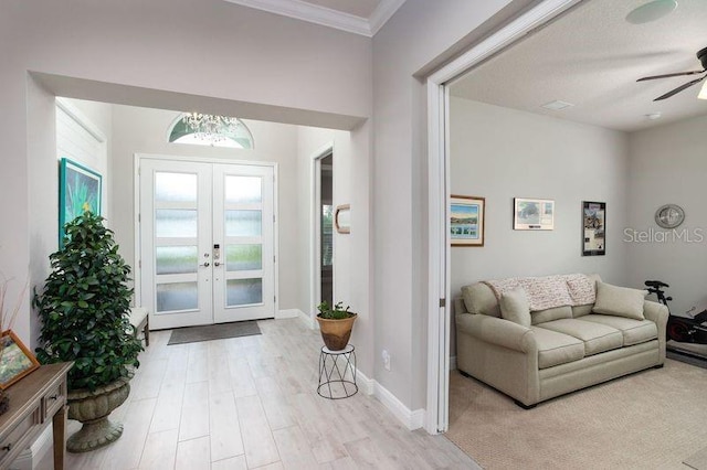 entrance foyer with ceiling fan, ornamental molding, french doors, baseboards, and wood finished floors