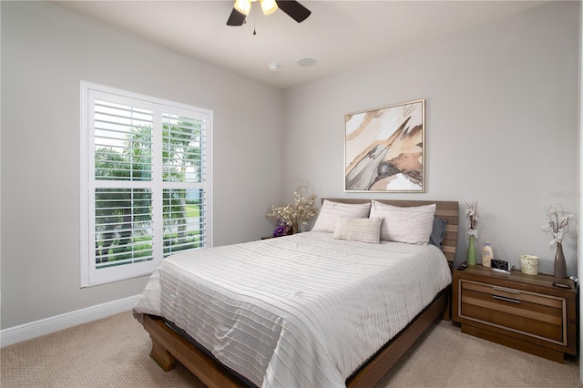 bedroom featuring light carpet, baseboards, and ceiling fan